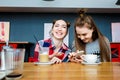 Two young beautiful hipster women sitting at cafe, stylish trendy outfit, europe vacation, street style, happy, having