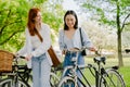 Two young beautiful smiling happy girls walking with bicycles Royalty Free Stock Photo