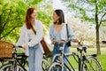 Two young beautiful smiling happy girls walking with bicycles Royalty Free Stock Photo