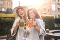 Two young beautiful smiling woman in summer clothes are having fun in city and drinking fresh cocktail Royalty Free Stock Photo