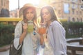 Two young beautiful smiling woman in summer clothes are having fun in city and drinking fresh cocktail Royalty Free Stock Photo