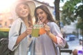 Two young beautiful smiling woman in summer clothes are having fun in city and drinking fresh cocktail Royalty Free Stock Photo