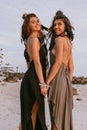 Two young beautiful stylish boho girls on the beach at sunset