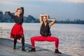 Two young beautiful twin sisters are dancing waacking dance in the city background near river. Royalty Free Stock Photo