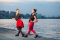 Two young beautiful twin sisters are dancing waacking dance in the city background near river. Royalty Free Stock Photo