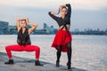 Two young beautiful twin sisters are dancing waacking dance in the city background near river. Royalty Free Stock Photo