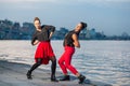 Two young beautiful twin sisters are dancing waacking dance in the city background near river. Royalty Free Stock Photo