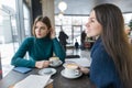 Two young beautiful women in cafe with cup of coffee talking in the break Royalty Free Stock Photo