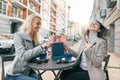 Two young beautiful women in an outdoor cafe with shopping bags and cup of coffee. Enjoying women looking at purchases Royalty Free Stock Photo