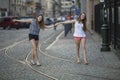 Two young best girlfriends walk along the tram tracks in the old town.