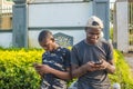 two young black men using their mobile phones outdoor, texting, and browsing the internet, smiling while using their phones Royalty Free Stock Photo