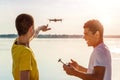 Two young bloggers operating drone with controller standing near the river Royalty Free Stock Photo