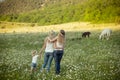 Two young blond lady in jeans and white undervest shirt walking across meadow of daisy chamomile with little girl holding hands we Royalty Free Stock Photo