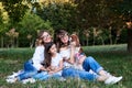 Two young blond women and one brunette girl, wearing jeans and white t-shirts, sitting on green grass in park, playing with Royalty Free Stock Photo