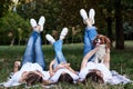 Two young blond women and one brunette girl, wearing white t-shirts, lying with their legs up on blanket on green grass in park, Royalty Free Stock Photo