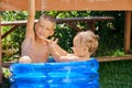 Two young boys enjoy a sunny day in an inflatable blue pool