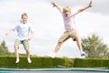 Two young boys jumping on trampoline smiling