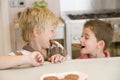Two young boys in kitchen eating cookies smiling Royalty Free Stock Photo