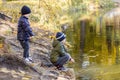 Two young boys playing fishing with sticks near pond in fall park. Little brothers having fun near lake or river in autumn. Happy Royalty Free Stock Photo