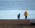 Two young boys in rain coats playing at the coast