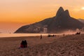 Two girls sat on Ipanema beach at sunset with Dois IrmÃÂ£os Two Brothers mountains in background in Rio, Brazil, South America Royalty Free Stock Photo