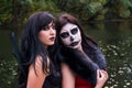 Two young brunettes women with makeup like a Halloween skull and