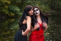 Two young brunettes women with makeup like a Halloween skull and