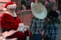 Two young buckaroo kids talk things over with Santa
