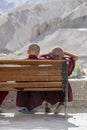 Two young Buddhist monk resting on a bench on the street next to the monastery Lamayuru in Ladakh, North India
