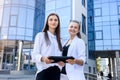 Two young business ladies posing outside office building. Women and business Royalty Free Stock Photo