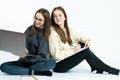 Two young business lady`s in casual clothes sitting on the ground with laptop and notebook, working together on a Royalty Free Stock Photo