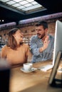 Two young business people, bloggers, sitting in modern office using desktop computer. Man and woman joyfully talking about project Royalty Free Stock Photo