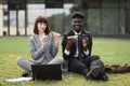 Two young business people having lunch break together, sitting on the grass outdoors Royalty Free Stock Photo