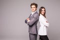 Full length of two young business people standing back to back with hands crossed isolated on grey background Royalty Free Stock Photo