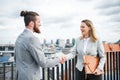 Two young business people standing on a terrace outside office, shaking hands. Royalty Free Stock Photo