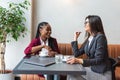 Two young business woman colleagues taking a break in nearby cafeteria drinking coffee talking about private life, to get know Royalty Free Stock Photo