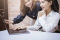 Two young business women are analytics information on laptop screen, business meeting