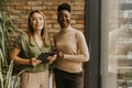 Two young business women with digital tablet standing by the brick wall in the industrial style office Royalty Free Stock Photo