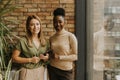 Two young business women with digital tablet standing by the brick wall in the industrial style office Royalty Free Stock Photo