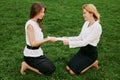Two young business women are fighting for a stack of blank papers against the backdrop of green grass. Outdoor photo Royalty Free Stock Photo
