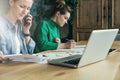 Two young business women sitting in office at table and work together.On table laptop and paper charts. Royalty Free Stock Photo