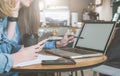 Two young business women sitting at table in cafe, drinking coffee and talking. First woman holding pen and smartphone Royalty Free Stock Photo