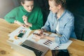 Two young business women sitting at table on which is laptop,smartphone,tablet computer,paper documents,graphics. Royalty Free Stock Photo