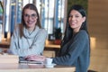 Two Young business women talking with each other about new projects at a coffee bar at caffe brake. Smiling into camera Royalty Free Stock Photo