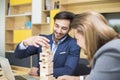 Two young businessmen build a wooden construction in the office