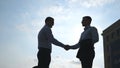 Two young businessmen meeting at city and greeting each other. Colleagues shake hands outdoor. Business handshake Royalty Free Stock Photo