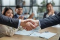 Handshake in agreement against young business people in board room meeting Royalty Free Stock Photo