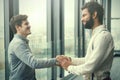 Two young businessmen shaking hands in modern office hall