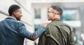 Two young businessmen smiling, talking and walking through the city together, excited for their new project. Happy Royalty Free Stock Photo