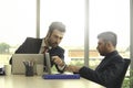 Two young businessmen using laptop computer seriously discussing about project work and communicating while sitting at the office Royalty Free Stock Photo